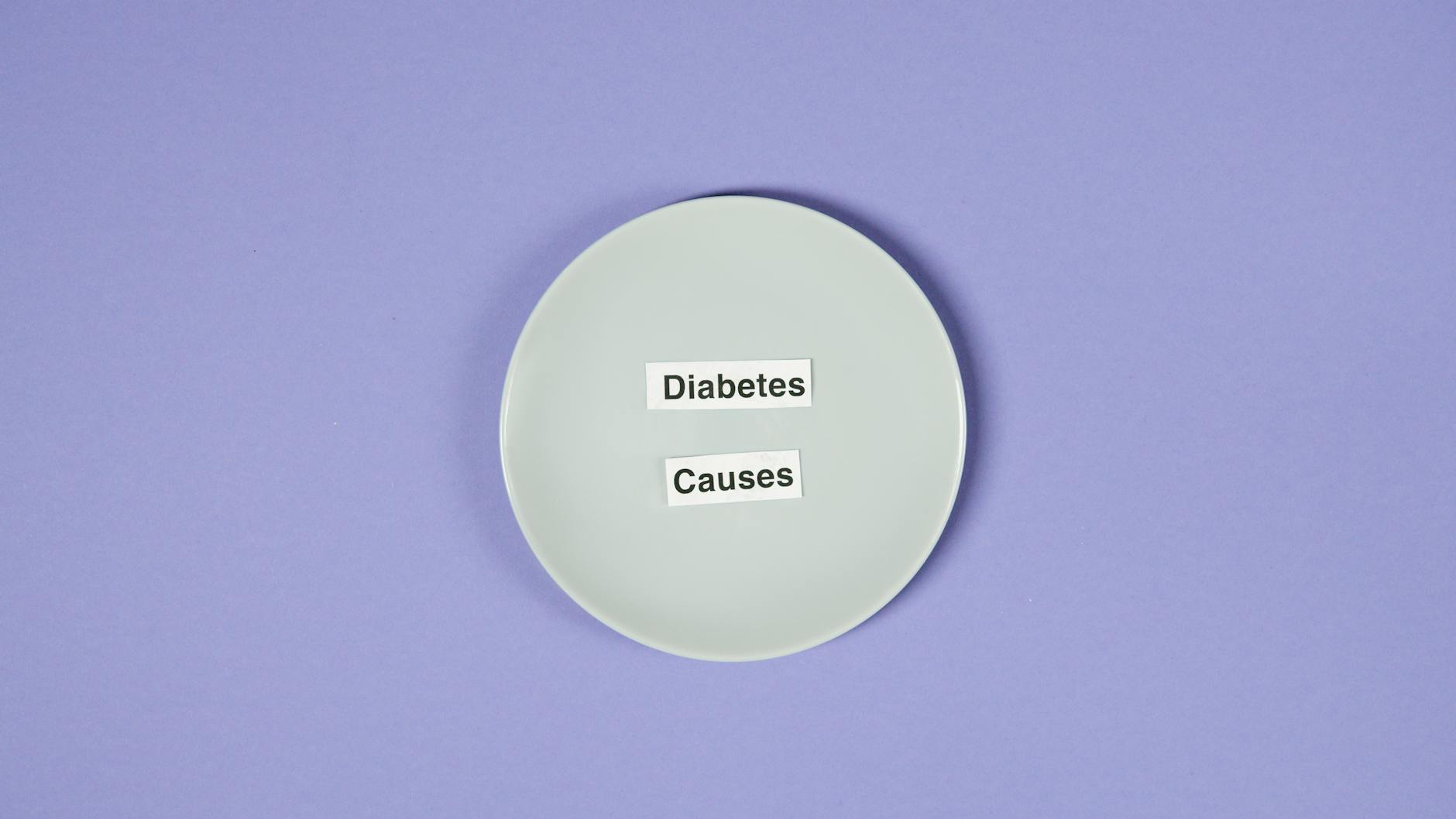 A conceptual photo of a white plate with diabetes causes text on a purple background.